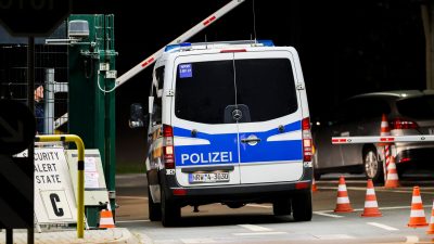 Ein Mannschaftswagen der Polizei fährt auf das militärische Gelände am NATO-Stützpunkt Geilenkirchen, links der Hinweis "Security Alert State C".