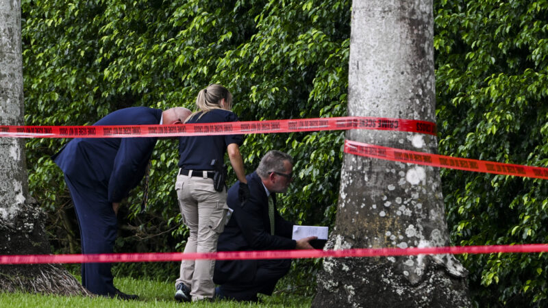 TOPSHOT - Law enforcement officials work at the crime scene outside the Trump International Golf Club in West Palm Beach, Florida, on September 16, 2024, following Sunday's attempted assassination on former US President and Republican presidential candidate Donald Trump. Ryan Wesley Routh, 58, was charged on Monday with possession of a firearm as a convicted felon and possession of a firearm with an obliterated serial number at his initial court appearance. (Photo by CHANDAN KHANNA / AFP) (Photo by CHANDAN KHANNA/AFP via Getty Images)