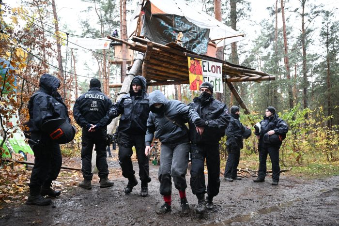 Ein Aktivist wird von Polizisten aus dem Protestcamp in der Nähe des Tesla-Autowerks in Grünheide abgeführt.