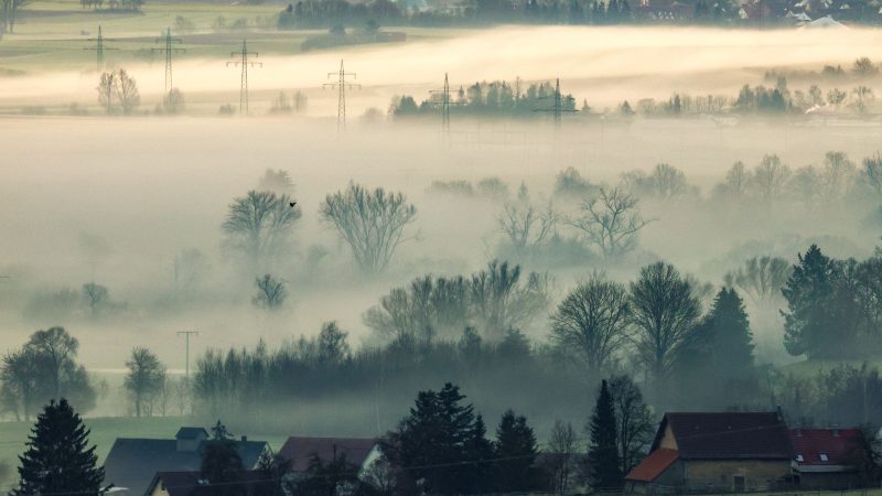 Bodennebel an der Donau hängt am Morgen bei Minusgraden im Gegenlicht der aufgehenden Sonne  in Riedlingen in Baden-Württemberg über der Landschaft.