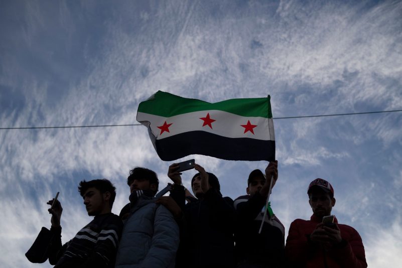 Syrer versammeln sich mit einer Fahne der syrischen Opposition in Damaskus.
