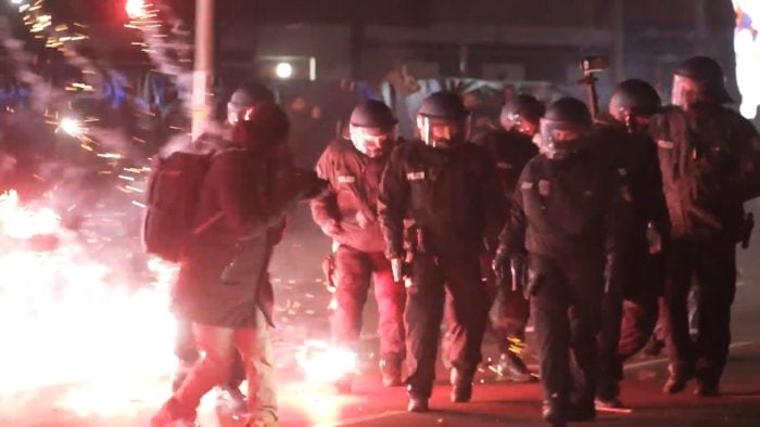 Polizei zwischen brennendem Feuerwerk auf der Straße in Berlin in der Silvesternacht. 