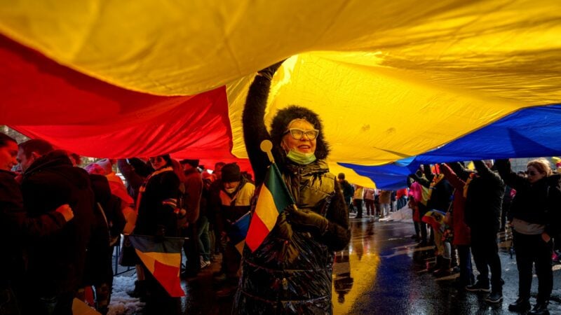 Anhänger von Georgescu, dem Gewinner der ersten Runde der rumänischen Präsidentschaftswahlen, die vom Verfassungsgericht für ungültig erklärt wurde, stehen unter einer rumänischen Fahne während einer Demonstration.