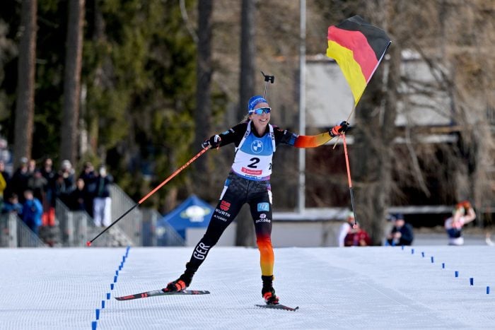 Franziska Preuß läuft mit der deutschen Fahne ins Ziel.