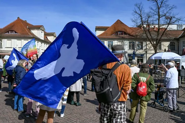 Friedenstauben sind auf Fahnen bei einem Ostermarsch zu sehen.