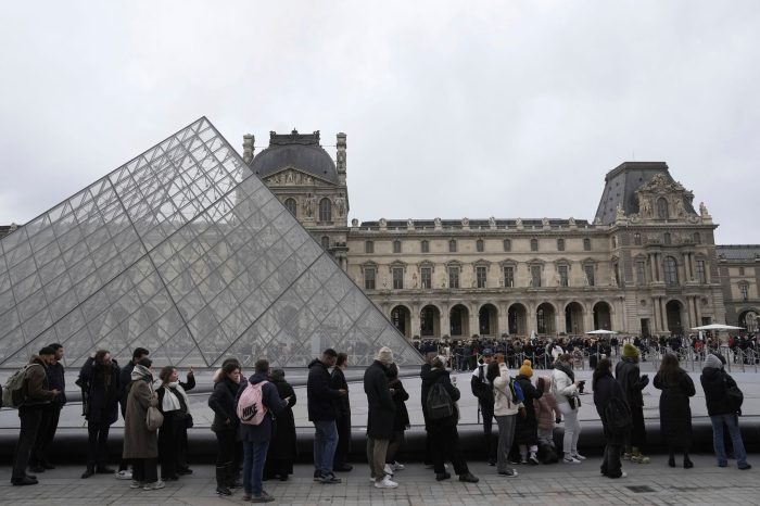 Menschen stehen vor den Louvre Schlange.