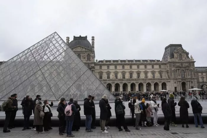 Menschen stehen vor den Louvre Schlange.