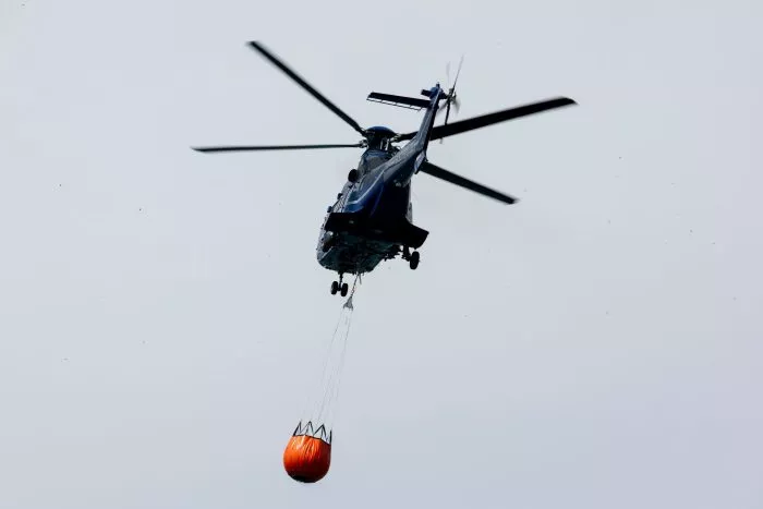 Ein Löschhubschrauber der Bundespolizei fliegt über dem Zeithainer Tagebau und nimmt Wasser auf, um den Waldbrand Gohrischheide zu bekämpfen.