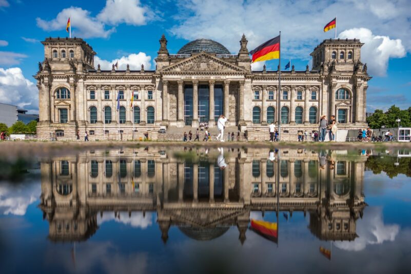 Das Reichstagsgebäude in Berlin, der Sitz des Deutschen Bundestags, spiegelt sich in einer Wasserpfütze.