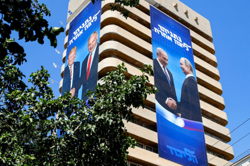 This picture taken on July 28, 2019 shows two giant Israeli Likud Party election banners hanging from a building showing Israeli Prime Minister Benjamin Netanyahu shaking hands with US President Donald Trump (L) and Russian President Vladimir Putin, with a caption above reading in Hebrew "Netanyahu, in another league", in the coastal Mediterranean city of Tel Aviv. (Photo by JACK GUEZ / AFP) (Photo by JACK GUEZ/AFP via Getty Images)