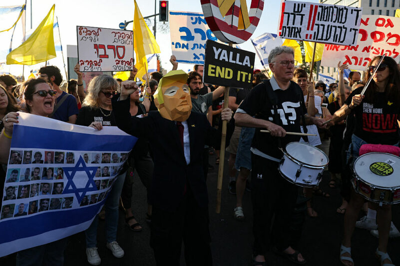 A demonstrator wears a mask in effigy of US President Donald Trump during an anti-government protest calling for action to secure the release of Israeli hostages held by Palestinian militants in the Gaza Strip since October 7, 2023, outside the prime minister's office in Jerusalem on August 7, 2025. (Photo by AHMAD GHARABLI / AFP) (Photo by AHMAD GHARABLI/AFP via Getty Images)