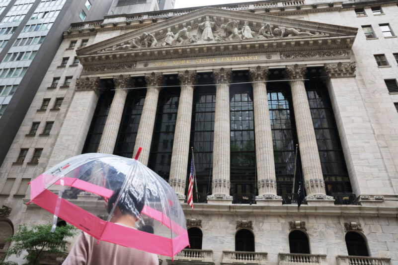 NEW YORK, NEW YORK - JULY 18: A person stands under an umbrella outside of the New York Stock Exchange during afternoon trading on July 18, 2023 in New York City. Stocks closed slightly high today with the Dow Jones closing over 300 points for its seventh straight day of gains and the longest winning streak since March of 2021, amid better than expected corporate earnings. (Photo by Michael M. Santiago/Getty Images)