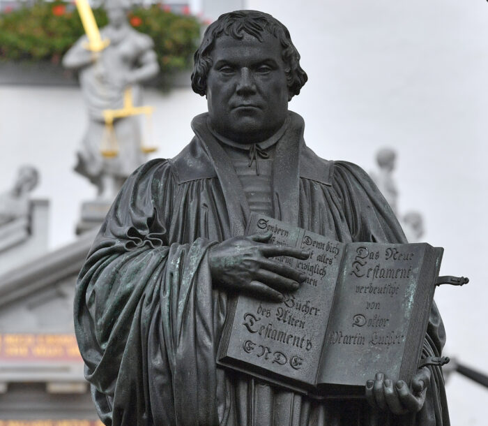 A statue of German Church reformer Martin Luther holding a book including his translation into German of the New Testament of the Bible is pictured at the main square in front of the city hall in Wittenberg, eastern Germany, where celebrations take place on the occasion of the 500th anniversary of the Reformation on October 31, 2017. - It is presumed that October 31, 1517 is the date that German theologian Martin Luther published his groundbreaking "95 Theses" of criticism of the Catholic Church, which marks the start of the process that led Protestants to break away from the Roman Catholic Church, a revolution for the Christian religion. The Reformation caused major upheaval in Europe, leading to wars, persecutions and exoduses, including the departure of the Pilgrims for what was later to become America. (Photo by Hendrik Schmidt / DPA / AFP) / Germany OUT (Photo by HENDRIK SCHMIDT/DPA/AFP via Getty Images)