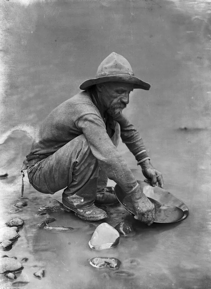 Mann sucht Gold mit Pfanne