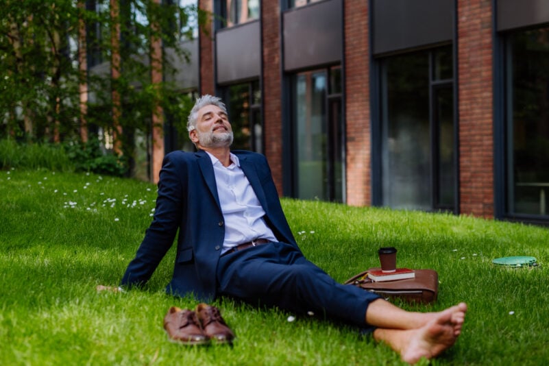 A mature businessman resting and sitting barefoot in park, feeling free, escaping from work, work life balance concept. Foto: Halfpoint/iStock