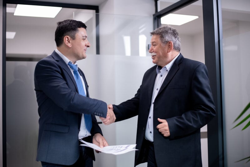 Colleagues exchange handshake symbolizing partnership and teamwork within a professional work setting. Foto: Nikola Spasenoski/iStock