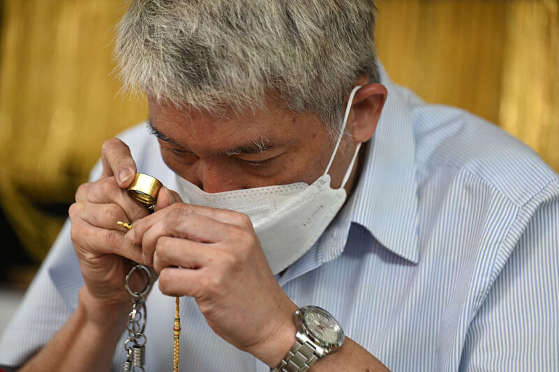 An employee inspects gold jewelry for customers at Hua Seng Heng gold traders in Chinatown in Bangkok on April 9, 2025. (Photo by Lillian SUWANRUMPHA / AFP) (Photo by LILLIAN SUWANRUMPHA/AFP via Getty Images)