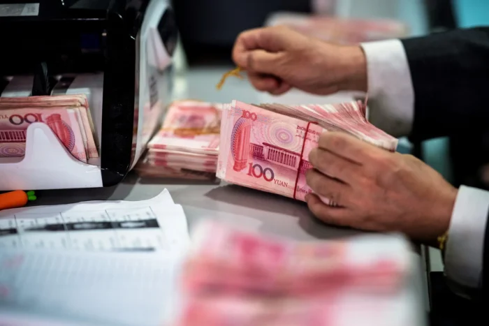 Ein Bankangestellter zählt am 8. August 2018 in einer Bank in Shanghai 100-Yuan-Scheine (etwa 14,60 US-Dollar). Das chinesische Regime führte im Jahr 2007 ein jährliches Devisenlimit von 50.000 US-Dollar pro Person ein und kündigte 2016 strengere Kontrollen bei der Umwandlung von chinesischen Yuan in US-Dollar an. Foto: Johannes Eisele/AFP via Getty Images