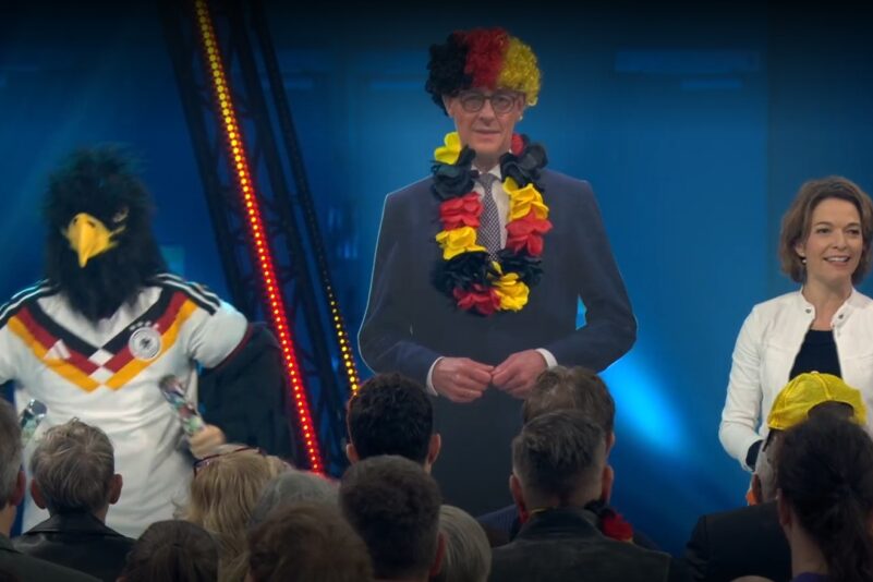 „Deutschlandmaskottchen“ Schlandi, Friedrich Merz als Pappfigur und Moderatorin Anna Planken feierten Deutschland. Foto: Bildschirmfoto/ARD-„Mediathek“