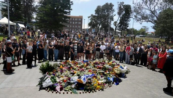 Menschen versammelt sich einen Tag nach einer Schießerei am Bondi Beach in Sydney um ein Blumendenkmal.